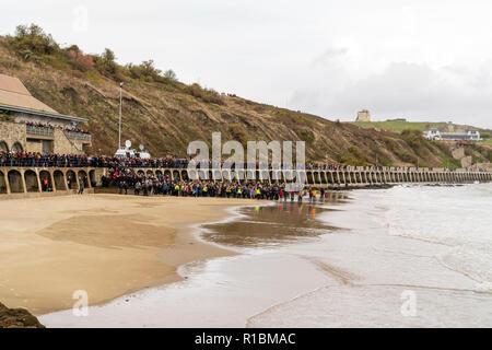 Folkestone, Kent, Angleterre. 11 novembre 2018. Les gens de la mer, sous un ciel gris, de regarder un portrait de sable de Wilfred Owen lentement été emportées par la marée montante. 100e anniversaire de la fin de la première guerre mondiale, le souvenir de l'événement Dimanche, 'Pages de la mer'. Banque D'Images