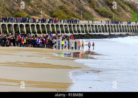 Folkestone, Kent, Angleterre. 11 novembre 2018. Les gens de la mer, sous un ciel gris, de regarder un portrait de sable de Wilfred Owen lentement été emportées par la marée montante. 100e anniversaire de la fin de la première guerre mondiale, le souvenir de l'événement Dimanche, 'Pages de la mer'. Banque D'Images