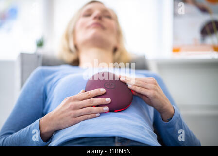 11 novembre 2018, en Rhénanie du Nord-Westphalie, Düsseldorf : une femme se trouve sur une table avec le 'stress' releaZer · de Beurer. Ce dispositif est très novateur qui combine l'aide de relaxation respiration ciblée et formation massage douce oscillation. 5 200 entreprises du monde entier vont présenter leurs produits et innovations dans le cadre du salon du 12 au 15 novembre. Photo : Guido Kirchner/dpa Banque D'Images