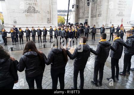 Paris, France. 11Th Nov 2018. Entouré d'école française Président français Emmanuel Macron allume la Tombe du Soldat inconnu sous l'Arc de Triomphe lors de manifestations marquant le centenaire de l'Armistice le 11 novembre 2018 à Paris, France. Le jour de l'Armistice marque la fin de la Première Guerre mondiale. crédit : Planetpix/Alamy Live News Banque D'Images