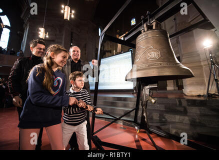 Mainz, Allemagne. 11Th Nov, 2018. Deux enfants peuvent sonner la cloche de la paix. L'artiste Michael Patrick Kelly (l) présenté dans le 'la Christuskirche PeaceBell', une cloche cast à partir de rebuts de la guerre. L'occasion est le 100e anniversaire de la fin de la Première Guerre mondiale. Crédit : Andreas Arnold/dpa/Alamy Live News Banque D'Images