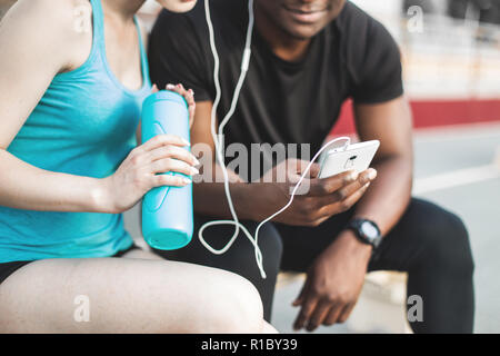 Un groupe d'athlètes assis sur le banc et de repos après une dure séance d'entraînement de la rue. L'homme et de la femme faisant sport urbain Banque D'Images