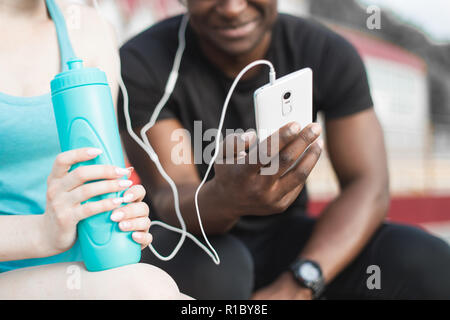 Un groupe d'athlètes assis sur le banc et de repos après une dure séance d'entraînement de la rue. L'homme et de la femme faisant sport urbain Banque D'Images