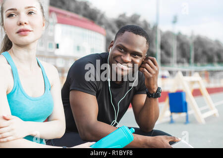 Un groupe d'athlètes assis sur le banc et de repos après une dure séance d'entraînement de la rue. L'homme et de la femme faisant sport urbain Banque D'Images