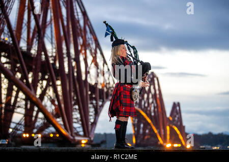 Louise Piper Marshall, vêtu d'un tartan rouge commémorative spéciale, joue Bataille, O'er, la lamentation écossais traditionnel joué à la fin de la bataille, à l'aube avec le Pont du Forth à North Queensferry sur le 100e anniversaire de la signature de l'Armistice qui a marqué la fin de la Première Guerre mondiale. Banque D'Images