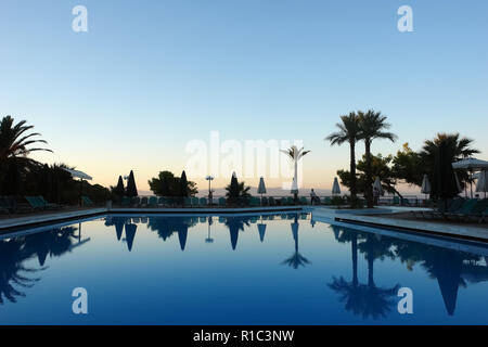 Scenic coucher du soleil au bord de la mer, bleu piscine et palmiers dans l'hôtel, péninsule de Kassandra, Grèce. Banque D'Images