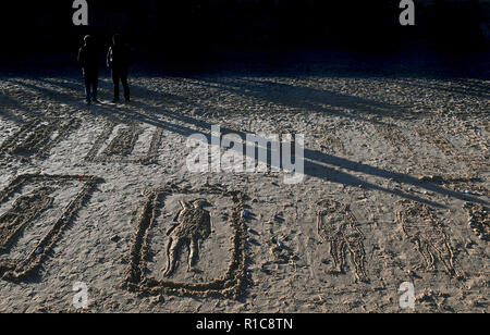 Personnes voir beach dessins sur les pages de la mer activité commémorative à Gorleston-on-Sea à Norfolk, sur le 100e anniversaire de la signature de l'Armistice qui a marqué la fin de la Première Guerre mondiale. Banque D'Images