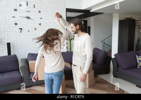 Jeune couple heureux mariés dansant ensemble dans la salle de séjour Banque D'Images