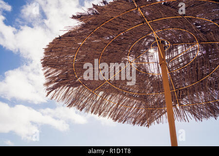 Plage paysage. Bambou, roseau, parasol de paille sur une journée ensoleillée sur la plage de sable. Location, vacances concept. Banque D'Images