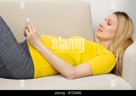 Pregnant woman lying on sofa Banque D'Images