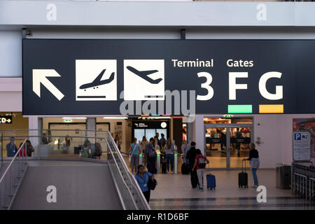 Un panneau lumineux à l'aéroport international de Vienne indiquant les indications pour les arrivées, les départs et les portes, les passagers avec des valises. Autriche Banque D'Images