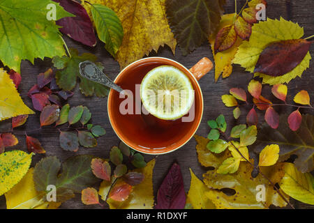 Une tasse de thé sur un fond de feuilles d'automne multicolore sur une surface en bois Banque D'Images