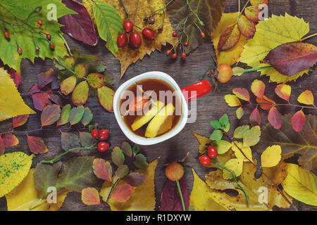 Une tasse de thé sur un fond de feuilles d'automne multicolore sur une surface en bois Banque D'Images