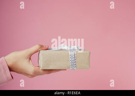 Boîte cadeau femme détient la main sur fond rose Banque D'Images