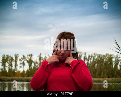 Une jeune femme gestouring près de la rivière en automne Banque D'Images