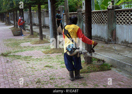 Les travailleurs de couper le gazon avec un siphon, Dumagette rajustage dispositif, aux Philippines. Banque D'Images