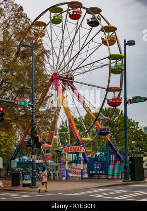 CHARLOTTE, NC, USA-11/08/18 : une grande roue riders attend une jeune femme passe devant, sur Tryon au 7e St. Banque D'Images