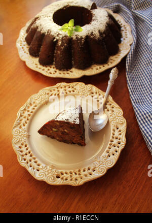 Bunt cake au chocolat saupoudré de sucre en poudre,fruits sur une plaque fond blanc . Banque D'Images