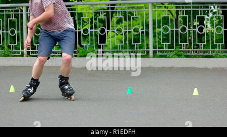 Boy riding sur rouleaux dans le parc d'été. Banque D'Images