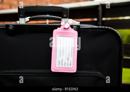 Vide féminin rose porte-étiquette bagage noir attaché à valise, remplissez l'étiquette, nom, adresse, téléphone du texte. Perdu, trouvé élément design concept. Banque D'Images