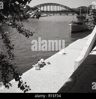 Années 1950, historiques, deux jeunes femmes assis à côté de la rivière sur une passerelle par la Seine, Paris, France. Banque D'Images