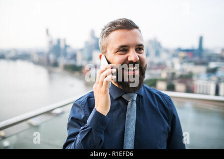 Un portrait of businessman with permanent smartphone contre Londres vue panorama. Banque D'Images