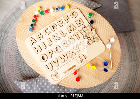 Pour l'alphabet en bois se trouve sur la table à côté du multi-couleur Peinture et pinceau. Vue d'en haut. Banque D'Images