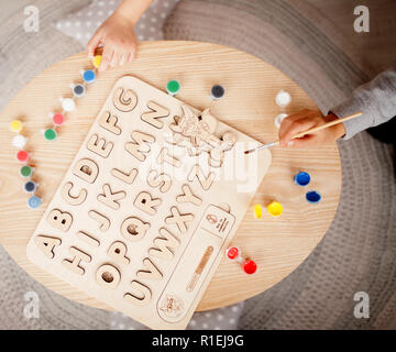 Pour l'alphabet en bois avec peintures multicolores se trouve sur la table à côté des enfants. Vue d'en haut. Banque D'Images