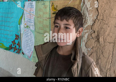 Boy est enseigné en anglais par Enseignante en Co-Educational School Situé à Hillside village troglodyte, province de Bamyan, Afghanistan Banque D'Images