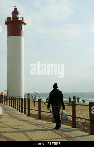 Durban, le KwaZulu-Natal, Afrique du Sud, seul mâle adulte pêcheur avec canne à pêche marche sur la promenade de destination de vacances uMhlanga Rocks Banque D'Images