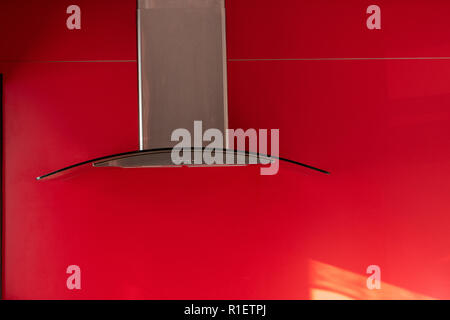 Cuisine faite avec rangehood l'arbre d'échappement chromé et verre incurvé hood sur un fond rouge Banque D'Images