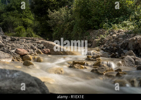 Rivière de montagne avec flux rapide et avec des ondes brouillées. Gros blocs de mousse dans l'eau claire. Banque D'Images