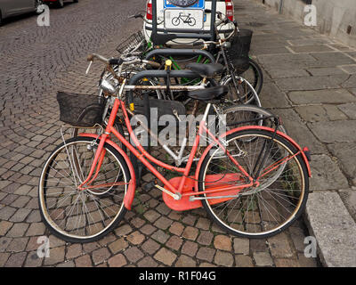 Vélo orange avec roue avant bouclée stationné à l'avant de la rangée de cycles au cycle classé dans rue pavée de Florence, Toscane, Italie Banque D'Images