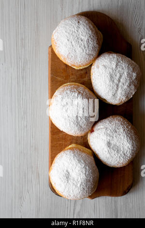 Des beignets sucrés faits maison avec la gelée et le sucre en poudre sur planche de bois rustique blanc sur fond de bois, vue de dessus. Copier l'espace. Banque D'Images