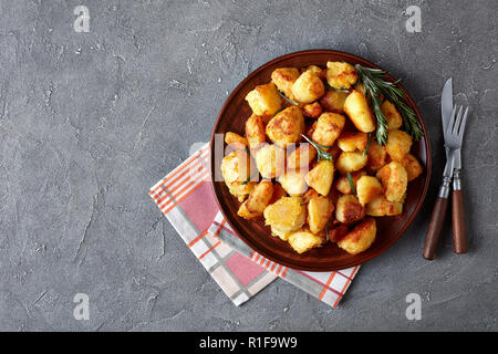 La farine de pommes de terre panées croquants aux épices et au romarin servi sur un plat d'argile et de serviette fourchette et un couteau sur une table, la vue d'un Banque D'Images