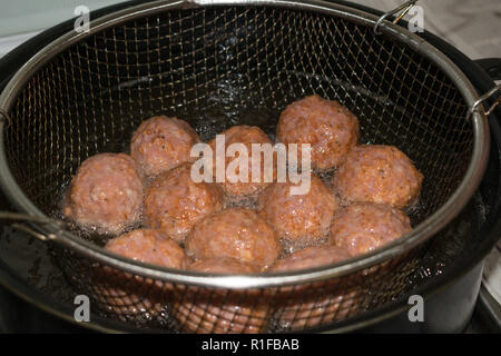 Faire frire les boulettes dans la friteuse remplie d'huile Banque D'Images
