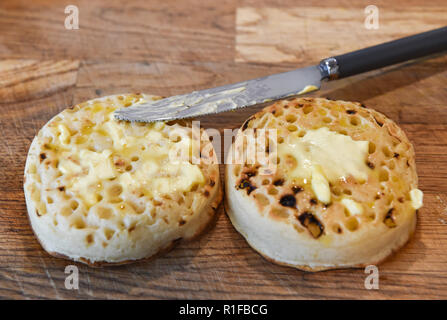 Les crumpets chauds grillés avec du beurre pour le petit déjeuner photographie prise par Simon Dack Banque D'Images