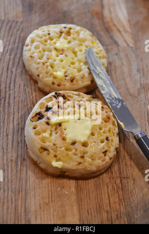 Les crumpets chauds grillés avec du beurre pour le petit déjeuner photographie prise par Simon Dack Banque D'Images