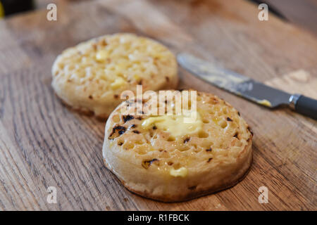 Les crumpets chauds grillés avec du beurre pour le petit déjeuner photographie prise par Simon Dack Banque D'Images