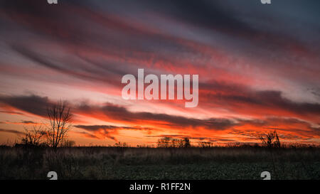 Les nuages passant par un coucher de soleil sur un champ plat, Banque D'Images