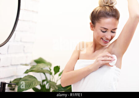 Jeune femme à l'aide de bains de déodorant Banque D'Images