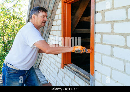 Man en bois peinture windows à l'aide de pinceau. La réparation de l'extérieur de l'ancienne maison. Close-up Banque D'Images