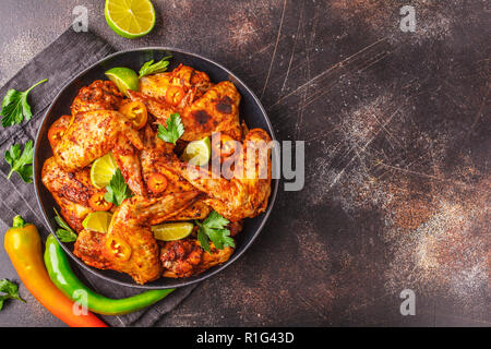 Ailes de poulet frit épicé au paprika sauce dans une plaque noire sur un fond sombre, vue du dessus, copiez l'espace. Banque D'Images