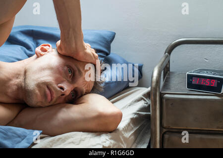 L'homme couché dans son lit. Préoccupante. Je ne peux pas dormir ou stressé Banque D'Images