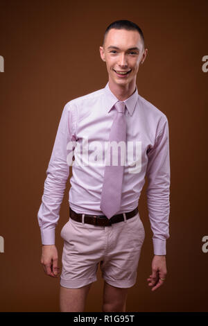 Beau jeune homme androgyne contre fond brun Banque D'Images