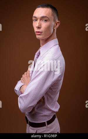 Beau jeune homme androgyne contre fond brun Banque D'Images