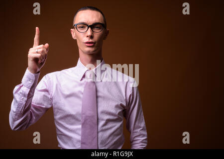 Beau jeune homme androgyne contre fond brun Banque D'Images