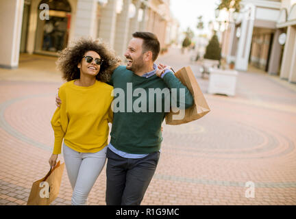 Charmante jeune couple multiethnique avec des sacs dans les magasins Banque D'Images