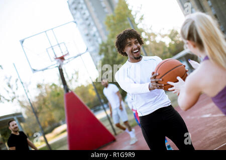 Couple multiracial jouant au basket-ball sur une cour au jour outumn Banque D'Images