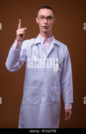 Beau jeune homme androgyne médecin contre fond brun Banque D'Images